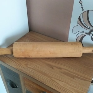 May include: A wooden rolling pin with a natural finish. The rolling pin is approximately 45 cm long and has a handle on each end.