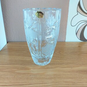 May include: A clear glass vase with a cut crystal design. The vase has a label that reads "Crystal Altplome".
