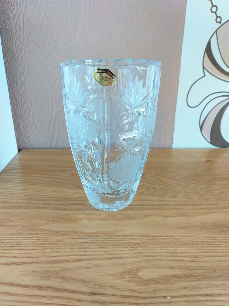May include: A clear glass vase with a cut crystal design. The vase has a label that reads "Crystal Altplome".