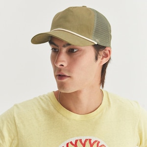 May include: A person wearing a yellow t-shirt with a red and white sun graphic that says "Sunshine" and a green and white mesh trucker hat.