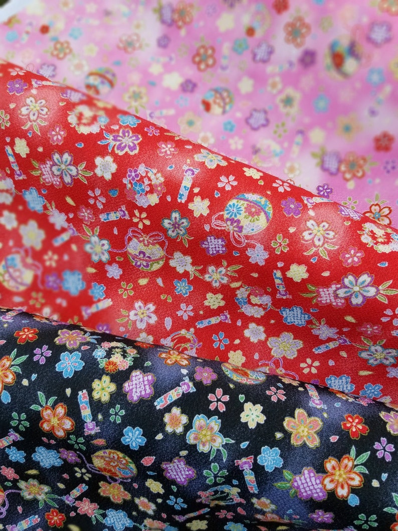 May include: Three fabric swatches with a repeating pattern of flowers and other designs. The top swatch is pink with white flowers, the middle swatch is red with white flowers, and the bottom swatch is black with white flowers.