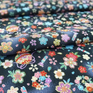 May include: Black fabric with a repeating pattern of colorful flowers and small ornaments. The fabric has a subtle sheen and a textured surface.