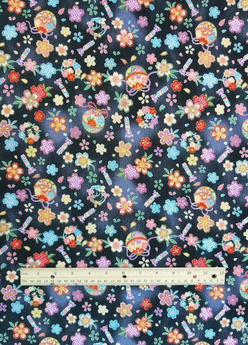 May include: Black fabric with a repeating pattern of colorful flowers, small balls with gold accents, and candy canes. The fabric is textured and has a subtle sheen.