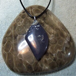 Könnte beinhalten: Ein dunkelvioletter und weißer Edelstein-Anhänger an einem schwarzen Lederband. Der Anhänger hat die Form einer Träne und eine silberne Öse.