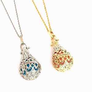 May include: Two teardrop-shaped cage pendants on thin chains. One pendant is silver-toned with a bright blue interior sphere, and the other is gold-toned with a coral-colored interior sphere. Both cages feature intricate cutouts and small crystals.