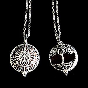 May include: Two silver-toned circular pendants hanging on matching link chains. The left pendant features an intricate geometric mandala pattern, while the right pendant displays a detailed tree of life design with visible roots and branches.