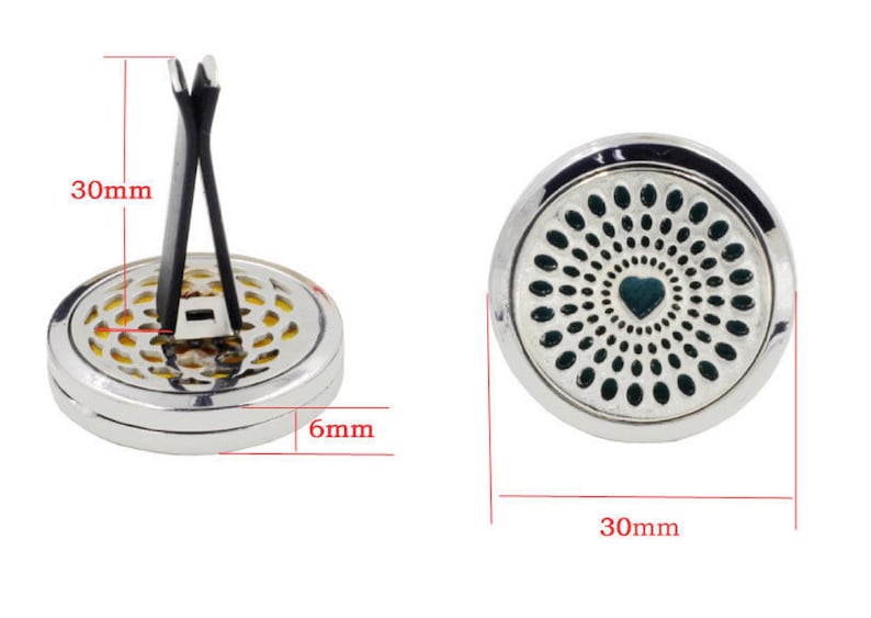 May include: Silver car air freshener with a black clip. The front of the air freshener has a green and silver design with a heart in the center. The air freshener measures 3 inches in diameter.