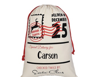 May include: A white canvas Santa sack with red drawstring. The sack has a black and red Rudolph Express stamp, the text "Deliver on December 25", and the text "Special Delivery for: Carson". The bottom of the sack has the text "Checked Twice By: Santa Claus".