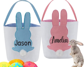 Puede incluir: Dos bolsas de lona en forma de conejo de Pascua con asas. La bolsa azul tiene el nombre "Jason" bordado y la bolsa rosa tiene el nombre "Amelia" bordado.