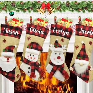 Può includere: Quattro calze di Natale personalizzate in tessuto a quadri rosso e nero. Le calze raffigurano Babbo Natale, un pupazzo di neve, una renna e un gnomo. Le calze sono appese a un camino con una ghirlanda di verde e campane rosse.