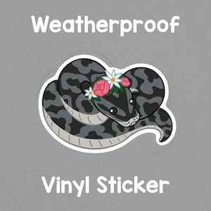 May include: A weatherproof vinyl sticker featuring a cartoon snake with a floral crown. The snake is gray with darker gray patterns. The sticker has the words "Weatherproof" and "Vinyl Sticker" in white.