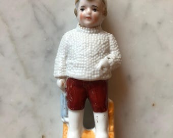 Estatueta de Natal antiga alemã de porcelana representando um menino na neve, década de 1930.