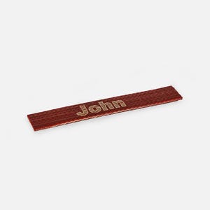 May include: A red woven label with the word "John" printed in gold.