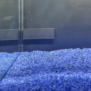 May include: A close-up of a blue aquarium substrate, a popular choice for freshwater aquariums. The substrate is made of small, round pebbles that provide a natural look and feel.
