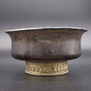 Puede incluir: Un cuenco de plata con un borde y una base dorados. El cuenco tiene una pátina oscura y está decorado con una banda de diseños intrincados alrededor de la base.