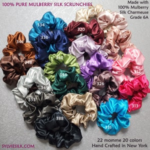 Pu&ograve; includere: Venti scrunchies di seta in vari colori, tra cui turchese, bordeaux, lavanda e rosa. Gli scrunchies sono realizzati in 100% seta di gelso charmeuse, grado 6A, e sono di 22 momme. Il testo "100% PURE MULBERRY SILK SCRUNCHIES" &egrave; nella parte superiore dell'immagine. Il testo "Made with 100% Mulberry Silk Charmeuse Grade 6A" &egrave; nella parte superiore destra dell'immagine. Il testo "22 momme 20 colors Hand Crafted in New York" &egrave; nella parte inferiore dell'immagine.
