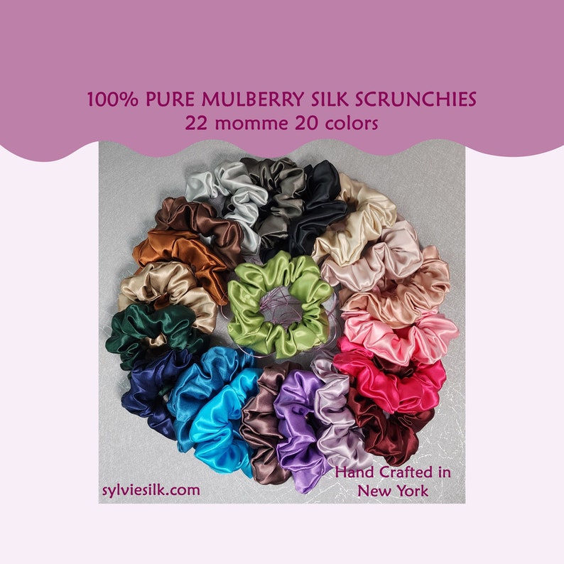 Pu&ograve; includere: Una collezione di 20 scrunchies di seta colorati disposti in cerchio. Gli scrunchies sono realizzati in seta di gelso 100% pura e hanno una momme di 22. Il testo "Hand Crafted in New York" &egrave; visibile nella parte inferiore dell'immagine.
