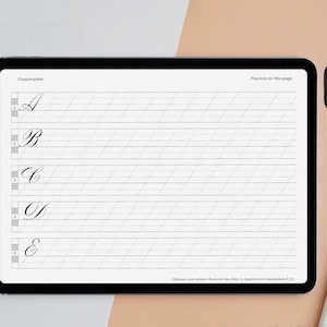 May include: A digital tablet displaying a calligraphy practice sheet with a grid pattern and the letters A, B, C, D, and E written in cursive. The app Procreate is visible in the upper right corner of the screen.