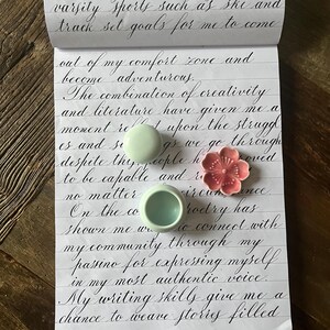 May include: A handwritten page of a journal with a quote about creativity and writing. The quote reads, "The combination of creativity and literature have given me a moment to reflect upon the struggles and successes as we go through despite the people we've encountered to be capable and resourceful. No matter the circumstance, poetry has shown me ways to connect with my community through my passion for expressing myself in my most authentic voice. My writing skills give me a chance to weave stories filled..."