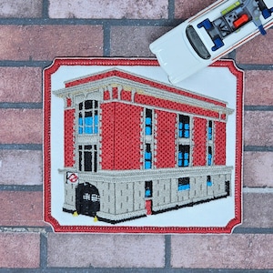 May include: A red brick building with white trim and blue windows. The building has a large, black door with a red fire hydrant in front of it. The building is surrounded by a white border with a red outline. The building is on a white background.