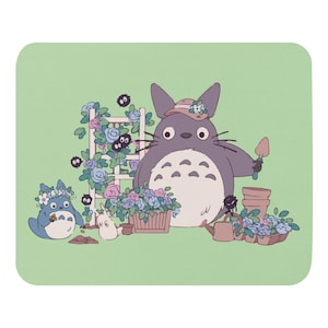 Może przedstawiać: Jasnozielona podkładka pod mysz z sceną ogrodową z postaciami Totoro. Obraz przedstawia Totoro w kapeluszu, trzymającego kielnię i pielęgnującego kwiaty. Obecne są również inne postacie, wraz z donicami i konewką.
