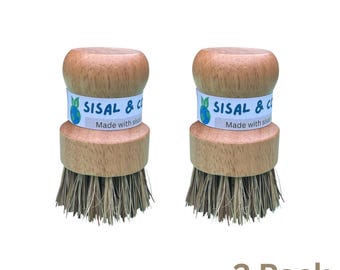 May include: Two wooden dish brushes with sisal bristles. Each brush has a light brown wooden handle and a band with the text "SISAL & CO" and "Made with sisal". The brushes are labeled "2 Pack".
