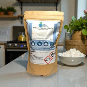 May include: A brown paper bag of Eco Earth Planet Sodium Percarbonate, a natural cleaner. The bag has a blue and white label with product information and safety symbols. A white bowl of the granular product sits nearby.