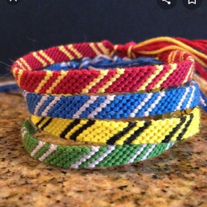 Puede incluir: Cuatro pulseras de la amistad en los colores de las casas de Hogwarts: Gryffindor (rojo y dorado), Ravenclaw (azul y plateado), Hufflepuff (amarillo y negro) y Slytherin (verde y plateado).