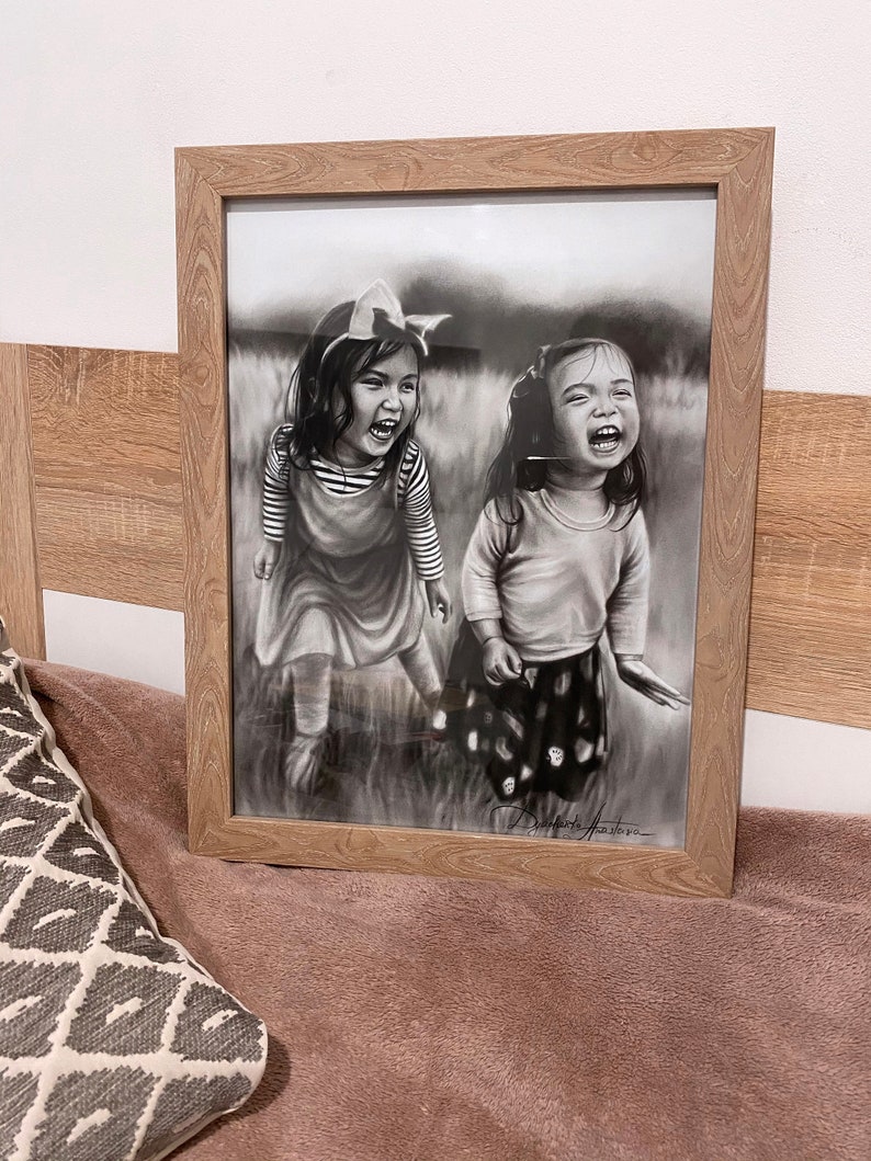May include: Black and white drawing of two young girls laughing in a field. The girls are wearing dresses and have their hair pulled back. The drawing is framed in a light wood frame.