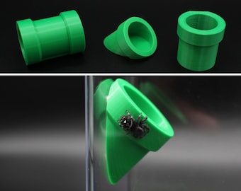 May include: Three green plastic 3D printed objects, a straight pipe, a curved pipe, and a cone-shaped pipe. The cone-shaped pipe has a small black spider inside.