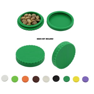 May include: Green, round container with a textured lid, shown open with seeds and closed. The text "SEEDS NOT INCLUDED" is visible. A variety of colored, round lids are displayed below the container.