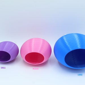 May include: Three ceramic nesting bowls in different sizes. The smallest bowl is purple, the middle bowl is pink, and the largest bowl is blue.