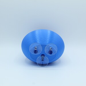 May include: A blue plastic planter with three suction cups on the bottom. The planter is designed to be attached to a smooth surface.