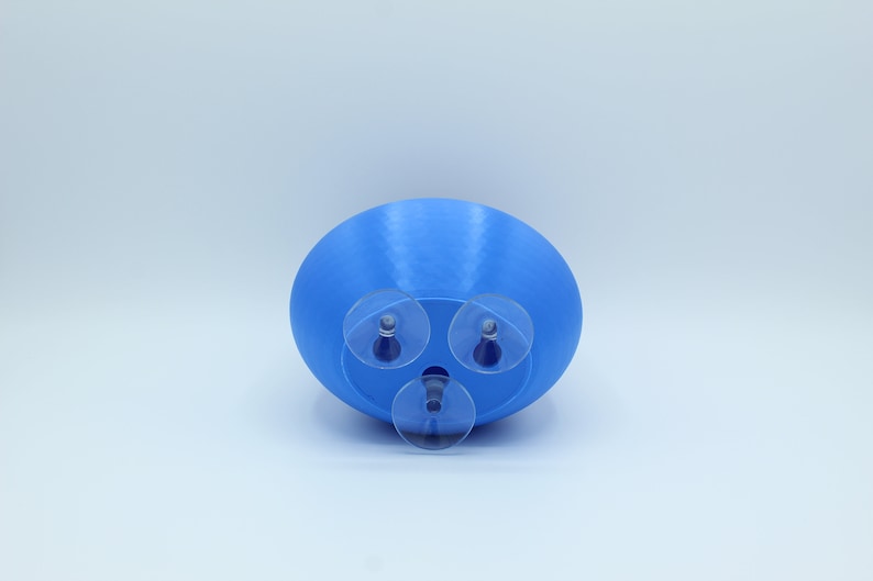 May include: A blue plastic planter with three suction cups on the bottom. The planter is designed to be attached to a smooth surface.