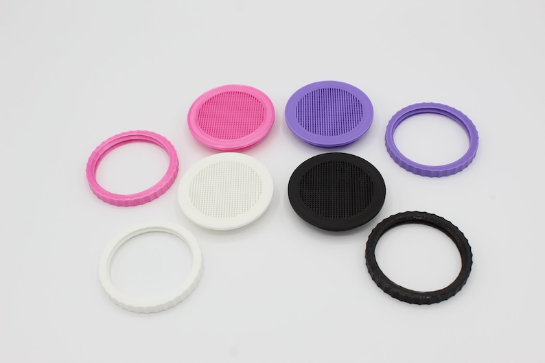 May include: Assortment of eight round plastic jar lids with different colors and designs. Some lids have a smooth surface, while others have a textured surface with small holes. The lids are in various colors, including pink, purple, white, and black.