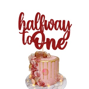 Puede incluir: Topper de pastel de purpurina roja con las palabras "halfway to one" para una celebraci&oacute;n de medio cumplea&ntilde;os.