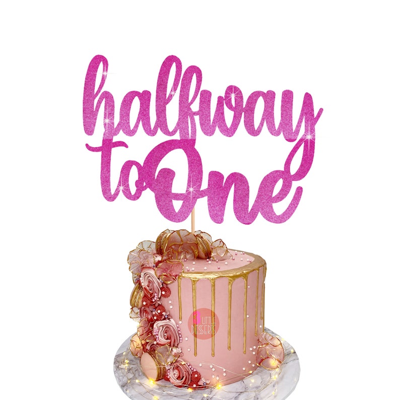 Puede incluir: Topper de pastel de purpurina rosa con el texto "halfway to one".