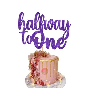Puede incluir: Topper de pastel de purpurina morada con el texto "halfway to one".