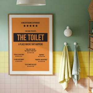 May include: A rectangular wall poster with an orange background and black text. The poster reads A BREATHTAKING EXPERIENCE, THIS HOME PRESENTS THE TOILET, A PLACE WHERE SHIT HAPPENS, and includes several five-star reviews with phrases like WILL KEEP YOU ON THE EDGE OF YOUR SEAT.