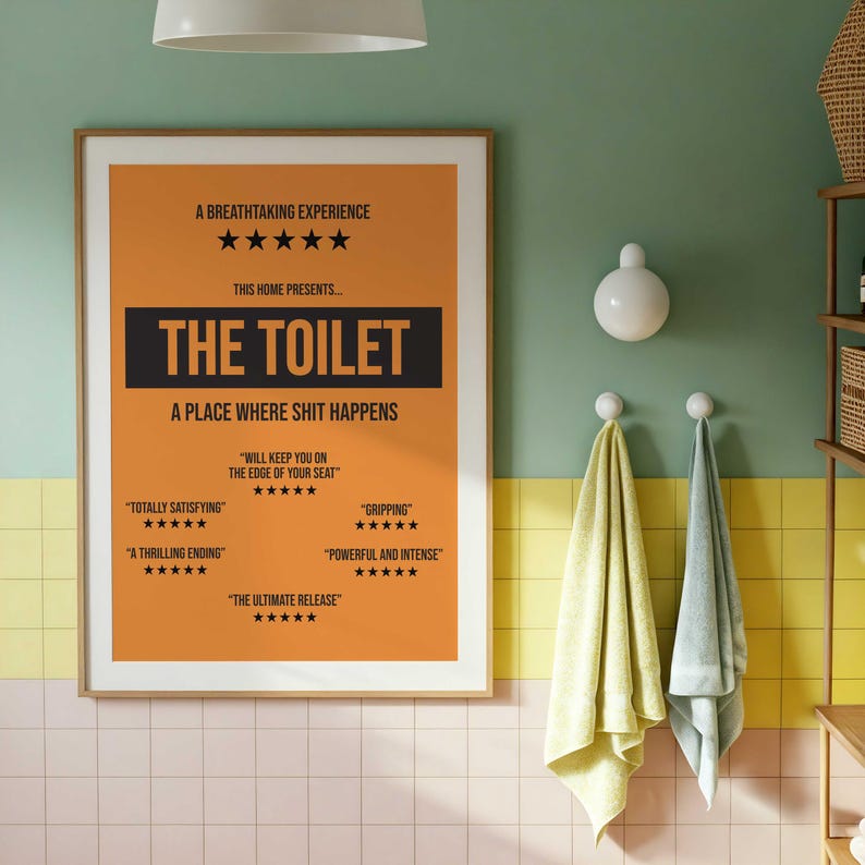 May include: A rectangular wall poster with an orange background and black text. The poster reads A BREATHTAKING EXPERIENCE, THIS HOME PRESENTS THE TOILET, A PLACE WHERE SHIT HAPPENS, and includes several five-star reviews with phrases like WILL KEEP YOU ON THE EDGE OF YOUR SEAT.