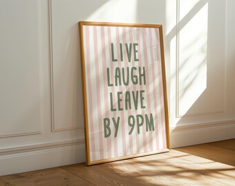 May include: A rectangular wall art print in a light wood frame featuring vertical light pink and white stripes. The text "LIVE LAUGH LEAVE BY 9PM" is printed in a bold, dark green, hand-drawn style font centered across the striped background.