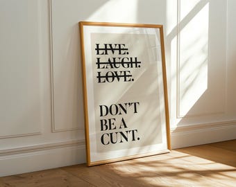 Peut inclure: Une affiche encadrée rectangulaire avec un fond beige et du texte noir. Les mots LIVE, LAUGH et LOVE sont écrits en format empilé avec une ligne horizontale barrant chaque mot. En dessous, le texte indique DON'T BE A CUNT.