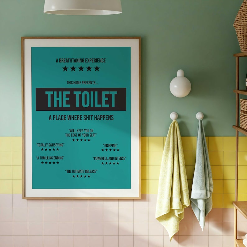 May include: A framed wall poster with a teal background and black text that reads: A BREATHTAKING EXPERIENCE, THIS HOME PRESENTS... THE TOILET, A PLACE WHERE SHIT HAPPENS, WILL KEEP YOU ON THE EDGE OF YOUR SEAT, TOTALLY SATISFYING, GRIPPING, A THRILLING ENDING, POWERFUL AND INTENSE, THE ULTIMATE RELEASE, all accompanied by five-star ratings.
