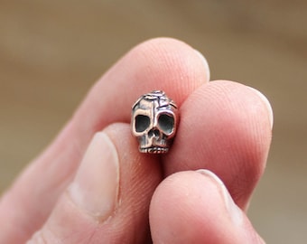 Perle tête de mort rose en plaque de cuivre antique. Étain Tierracast.