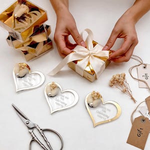 May include: A gold-trimmed square gift box tied with a cream ribbon, surrounded by heart-shaped acrylic tags with dried flowers and pearl accents. Each tag features the text Thank you for celebrating with us. Includes metal scissors and gift tags.