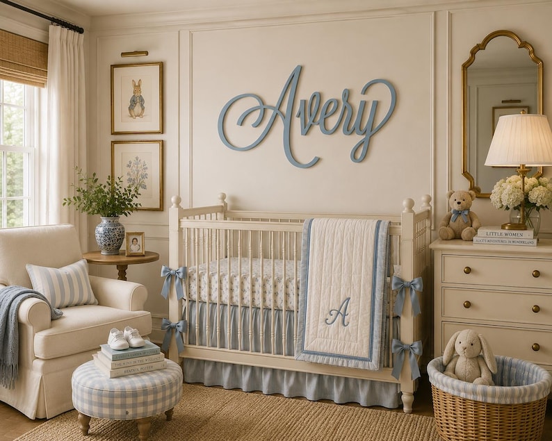 May include: A nursery room featuring a white crib with a blue and white quilt monogrammed with the letter A, a blue wooden name sign reading Avery on the wall, a cream armchair, a blue gingham ottoman, and a wicker basket with a plush rabbit.