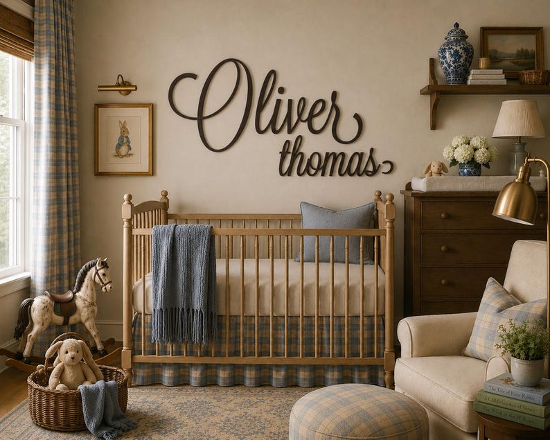 May include: A dark brown wooden wall sign featuring the name Oliver Thomas in a cursive script font, mounted above a light wood crib with a blue plaid skirt, a blue throw blanket, and a gray pillow in a nursery setting.