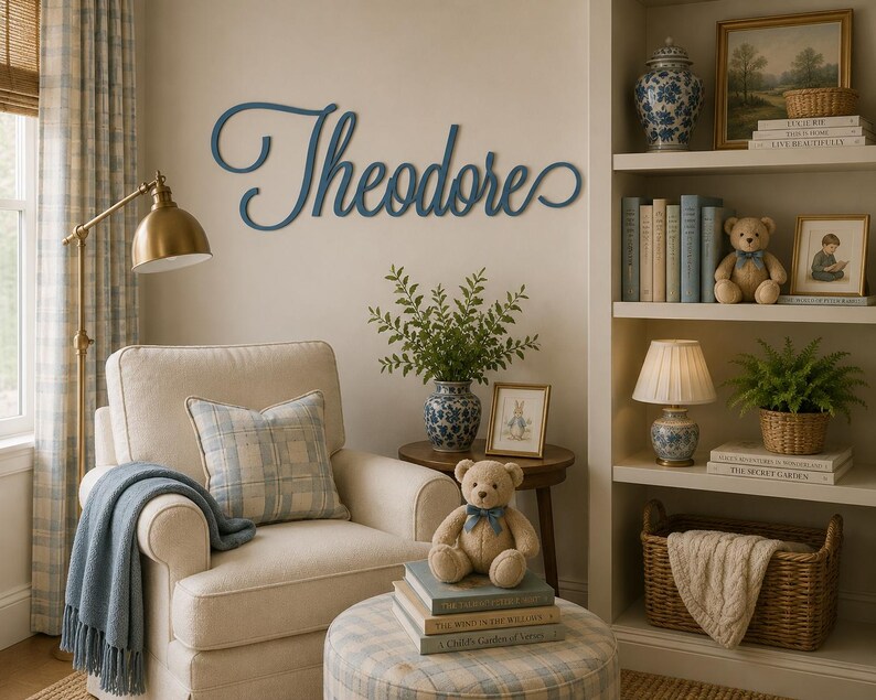 May include: A dark blue wooden wall sign featuring the name Theodore in a cursive script font. The letters are connected in a flowing style and mounted on a plain wall above a cream-colored armchair, a small wooden table, and a bookshelf.