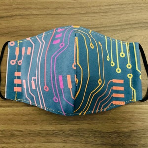 May include: A blue face mask with a colorful circuit board design. The mask has a black elastic band.