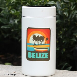 May include: White travel mug with a sticker featuring a sunset scene with palm trees and a boat. The sticker says "Belize" in turquoise text.